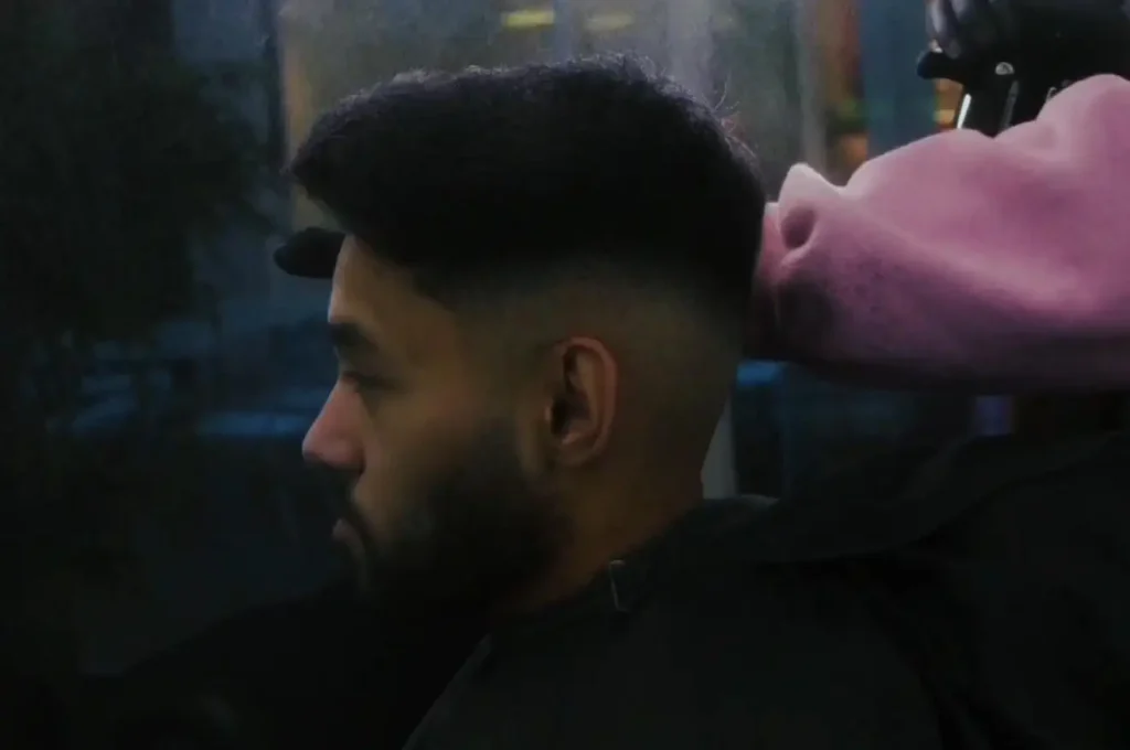 Skin fade close up with barber wearing pink hoodie.
